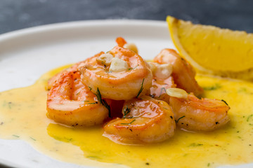 Tiger prawns on the grill with sause and lemon on dark grey concrete table