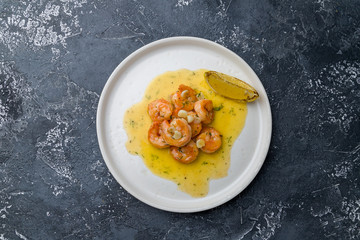 Tiger prawns on the grill with sause and lemon on dark grey concrete table