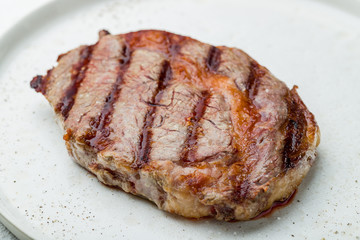 juicy Ribeye steak on white plate on white concrete table