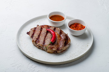 juicy Ribeye steak on white plate on white concrete table