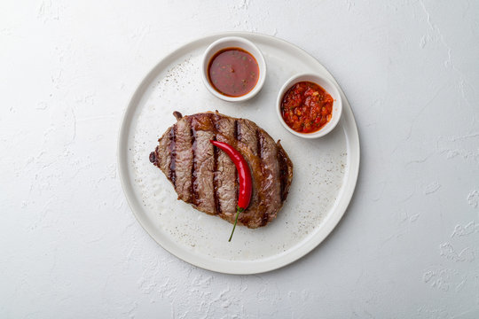 Juicy Ribeye Steak On White Plate On White Concrete Table