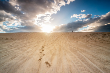 Fototapeta na wymiar Star burst and person on sand dune, Stockton Sand Dunes, NSW, Australia