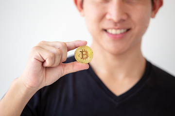 Young asian man hold golden bitcoin coins in hand. Virtual currency. Crypto currency. New virtual money.