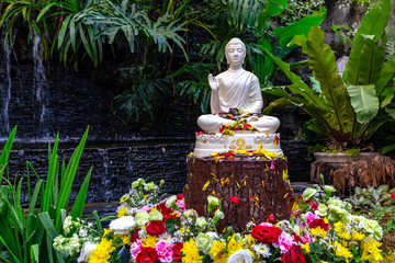 Small home garden private fountain pond with meditating Buddha statue between trees and bushes. Private zen garden concept. Songkran Thai famous festical concept. 