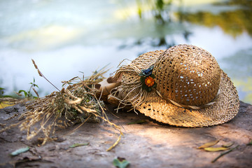straw hat with a bouquet of flowers on a background surface of the water