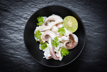 squid salad bowl with lime herbs and spices on black background top view - Tentacles octopus cooked appetizer food seafood cooked in the restaurant