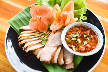 Roasted pork - sliced baked pork grilled with spicy sauce and sticky rice herbs spices ingredients fresh vegetable served on plate in the wooden table , Thai Asian food