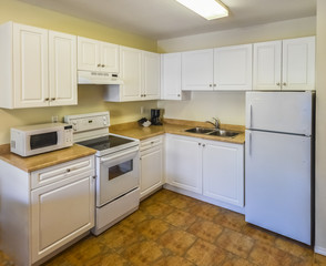 Conventional white kitchen with the table and chairs in dinner area.
