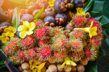 Fototapeta premium Summer fruit with rambutan longkong mangosteen in the basket on banana leaf background with flowers - Thai fruit