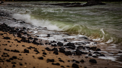 Gentle waves crash on a rocky beach in Hawaii