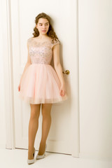 Obraz na płótnie Canvas Girl teenager in a smart dress standing near the white door.