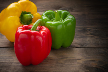 Red, green, yellow, sweet bell pepper on wooden background.