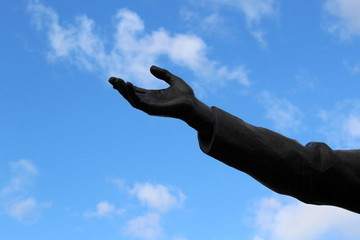 Bronze hand of a statue against the sky