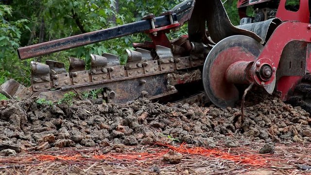 Hydraulic arm of a trenching machine raises up exposing the metal blade used to dig irrigation and utility trenches before machine moves away.