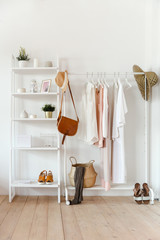 Clothing in trendy color hangs on a rack with accessories, and there is a rack with interior items