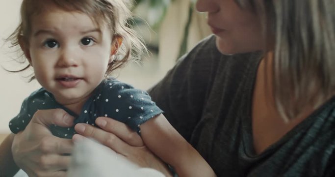 Mother playing with daughter at home on the couch. Real life, candid footage. Shot in 4K RAW on a cinema camera.