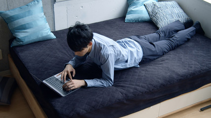 ベッドでPCを使う男性