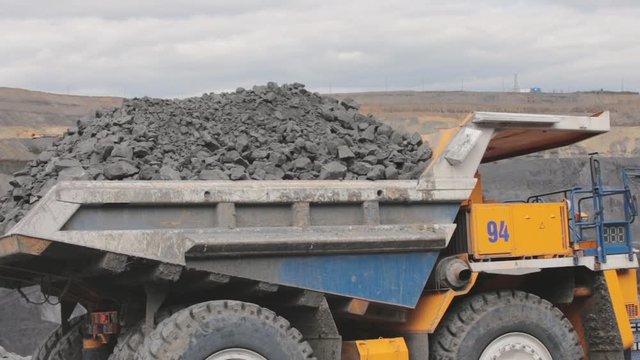 A huge mining truck is carrying coal. Open pit coal mining