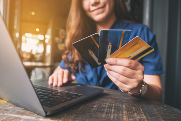 Closeup image of a woman holding and choosing credit cards while using laptop computer