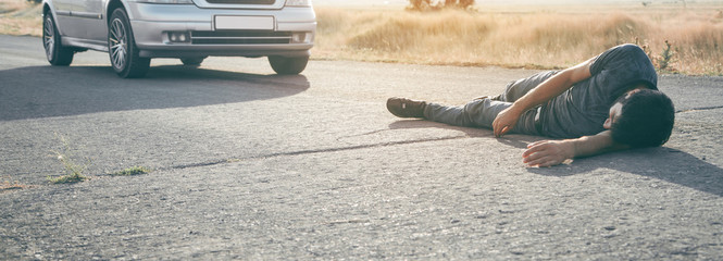 Caucasian injured man lying on asphalt.