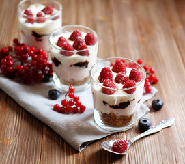 Healthy breakfast - yogurt with fresh berries and muesli served in glass jar, on wooden background