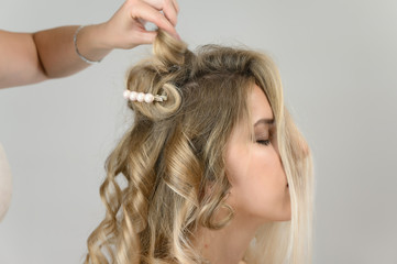 Naklejka premium A photo of a hairdresser working on a model's hair in a studio. Makes a hairstyle, styling hair on a white background.