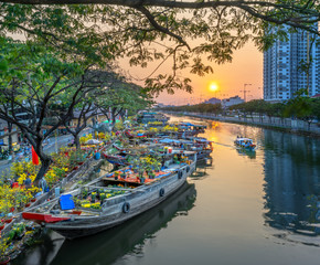 Fototapeta na wymiar Ho Chi Minh City, Vietnam - February 3rd, 2019: Sunset boat dock flower market along canal wharf. This is place farmers sell apricot and other flowers on Lunar New Year in Ho Chi Minh city, Vietnam