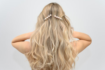 Fototapeta premium A large photo portrait of a pretty model with long hair and a beautiful hairstyle on a white background. Back view.