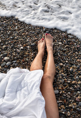 Summer holiday fashion concept - tanning woman sitting at the beach on a pebbles shot from above.