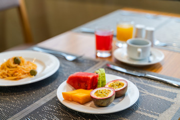 Fresh romantic breakfast table next to morning briliant light window, with spaghetti, fruit, juice