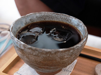陶器のカップで飲むアイスコーヒー