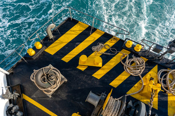 The deck of the ferry boat along with the a thick mooring rope and blue sea water wave, Thailand....