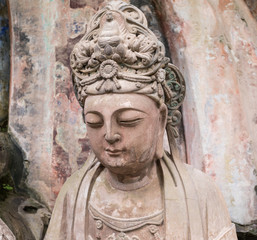 Fototapeta na wymiar Statue of disciple or follower in front of giant Buddha at Dazu Rock Carvings at Mount Baoding or Baodingshan in Dazu, Chongqing, China. UNESCO World Heritage Site.