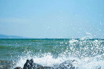 Image of the sea shore. In the background is a warship.