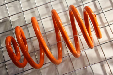 Close up new orange variable diameter car spring, automotive suspension part