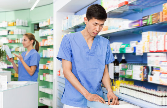 Man pharmacist is searching medicine in drawers in apothecary.