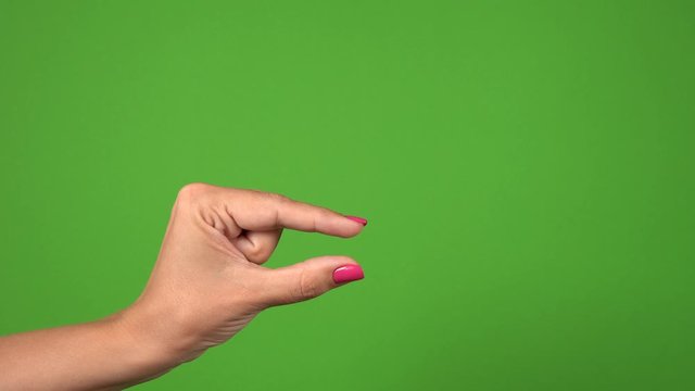Closeup view of female one hand showing different sizes of invisible virtual objects by her fingers from very small to very big. Hand isolated on green background. Real time 4k video footage.