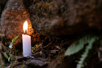 Small candle on the rock, with some leaves around