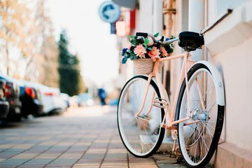 Fotobehang Witte fiets met bloemenmand bij de deur op straat in de stad © B@rmaley