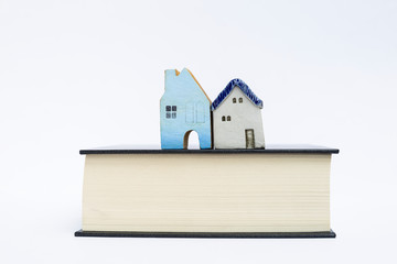 Design miniature house on thick book isolate on white background, property and real estate business object