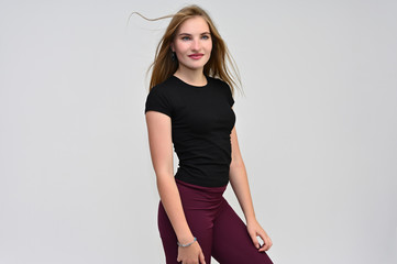A knee-length portrait of a pretty brunette girl with long flowing hair in a black T-shirt and...