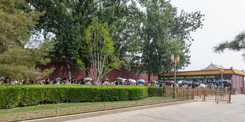 Long line of tourists in front of the security checkpoint for entering into Tiananmen Square and Forbidden City in a hot, hazy summer day in Beijing, China.