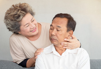 Smiling senior woman stand behind elderly man.  Loving wife comforting troubled husband. Concept of depressed, unhappy and reconcile.