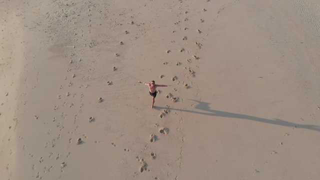 Aerial shoot The sports guy runs on a thin stripe of sand among the ocean