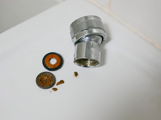 Close up of a disassembled parts of a rain shower head getting clogged with mineral deposits,...