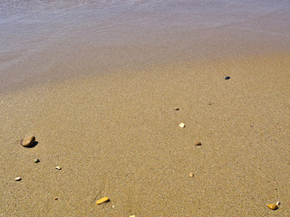 Fototapeta na wymiar Sandy beach with some pebbles close up detail.