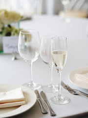 Table served for banquet with cutlery, wine glasses and napkins. Pastel colored decorations.