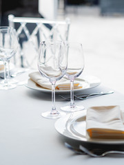 Table served for banquet with cutlery, wine glasses and napkins. Pastel colored decorations.