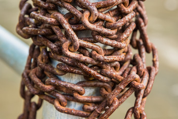 Old rusty chains on a steel pole.
