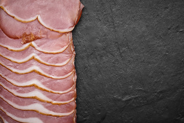 sliced italian prosciutto on black stone background. top view